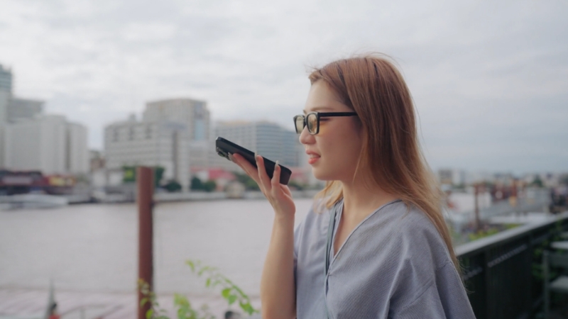 A woman uses voice search on her smartphone outdoors