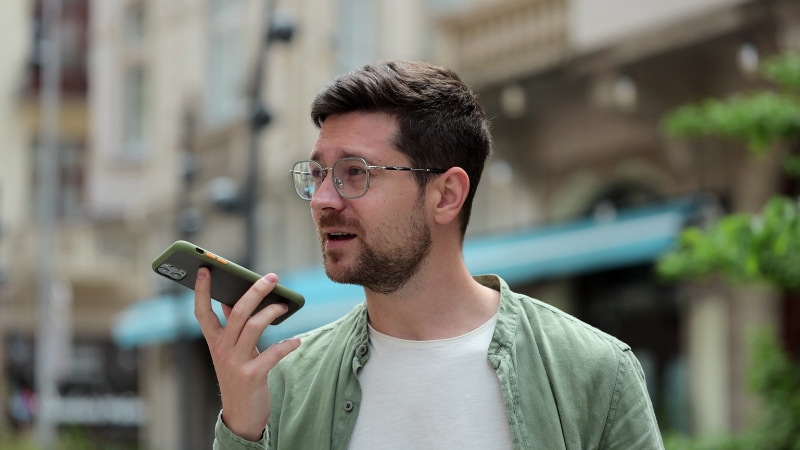 A man uses voice search on his smartphone outdoors