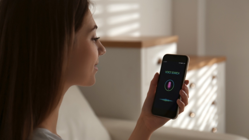 A woman uses voice search on her smartphone, showing the need for mobile-first optimization for voice users