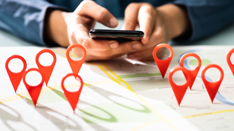 A person uses a smartphone over a map with location markers, showing the importance of strong local citations and directory presence